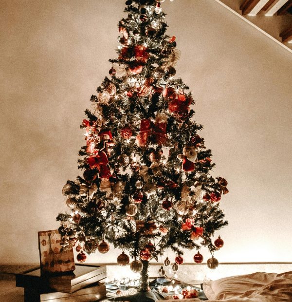 Traditional home Christmas tree in UAE decorated with red baubles, warm fairy lights, and a dark star topper.